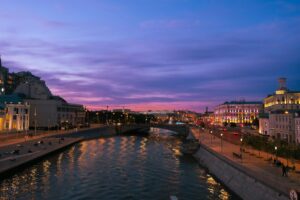 Discover Moscow's vibrant riverfront with city lights reflecting at sunset, capturing the essence of a beautiful evening in Russia.